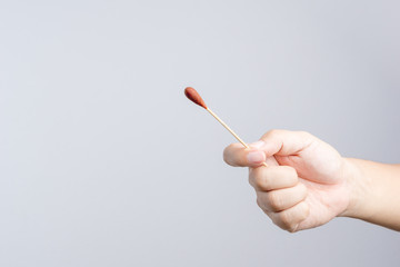 Hand holding Povidone iodine swab made of wooden stick and cotton wool for first aid