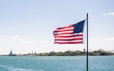 An America flag is flying on the background of Pearl Harbor