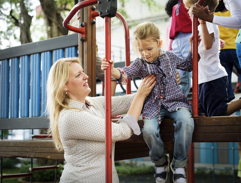Teacher taking care of kindergarten girl at playground