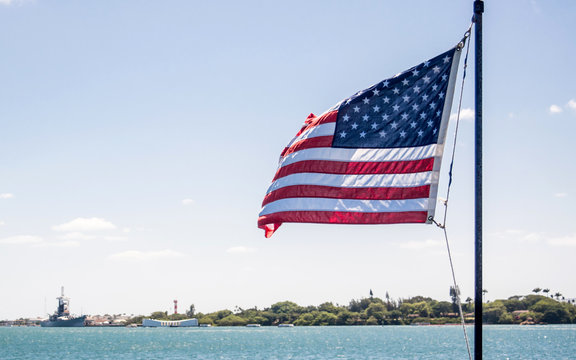 An America flag is flying on the background of Pearl Harbor