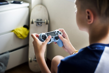 Young caucasian boy holding game control sitting on bed © Rawpixel.com