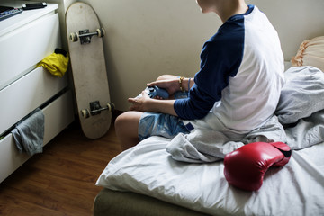 Young caucasian boy holding game control sitting on bed © Rawpixel.com