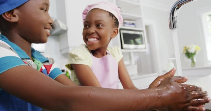 African American girl children washing hands in kitchen