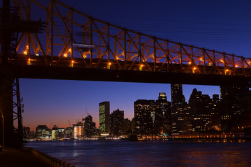 Manhattan and Roosevelt Island bridge at night in New York, USA. A view on Manhattan from the East River bank at night.