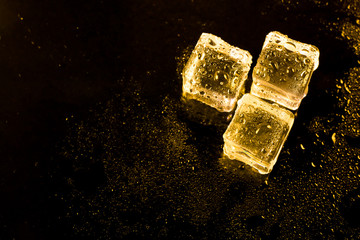 ice cubes and water drop on light golden background.