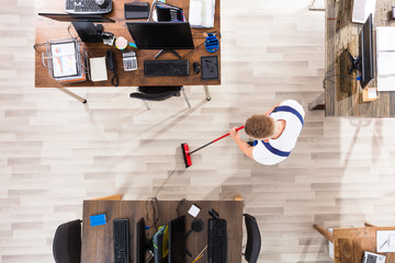 Janitor Cleaning Floor With Broom In Office