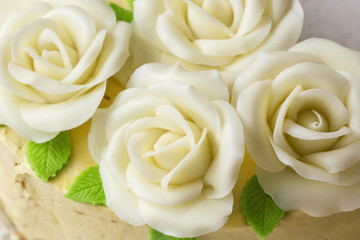 Marzipan roses on a cake with green leaves.
