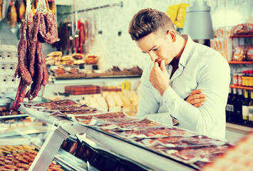 Young man choosing what kind of meat to buy