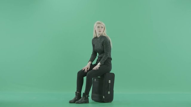 a girl is sitting on the luggage and waiting