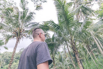 Portrait of a traveler man in sunglasses in the tropical jungle of Bali island, Ubud, Indonesia.