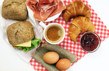 breakfast on table with bread rolls, croissants, coffe and eggs