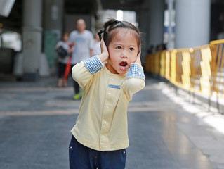 Cute little child girl shutting down her ears, holding her hands covers ears not to hear.