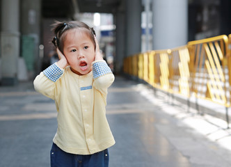 Cute little child girl shutting down her ears, holding her hands covers ears not to hear.