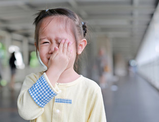 Child girl closing hid eyes by hand.