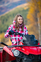 Fototapeta na wymiar Portrait of pretty woman in winter clothing on red quad bike looking in the distance on the blurred background nature
