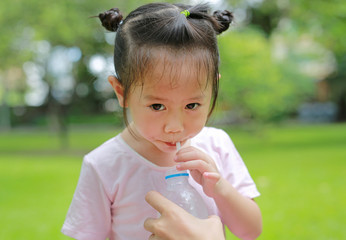 Close Up little girl drinking water in the park. Portrait outdoor.