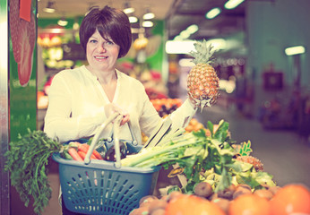 Middle aged woman with basket choosing fruits