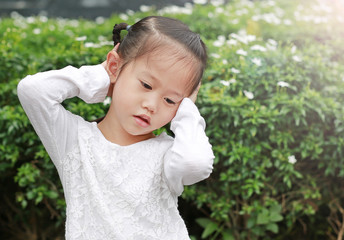 Cute little child girl shutting dawn her ears, holding her hands covers ears not to hear.