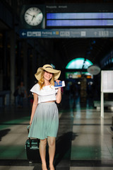 Fototapeta premium Charming girl in sun-hat in the waiting room of the train station.