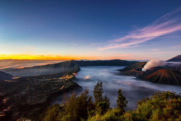 Bromo volcano park with twilight sunrise sky background and fog landscape.