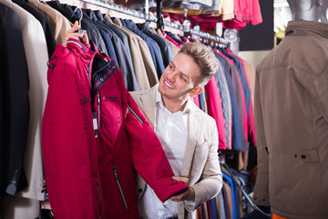 Cheerful male customer examining coats