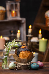 Festive cupcake with a bouquet of valley lilies on a background of candles