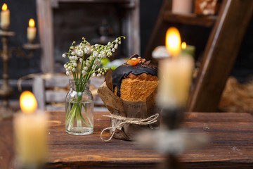 Festive cupcake with a bouquet of valley lilies on a background of candles