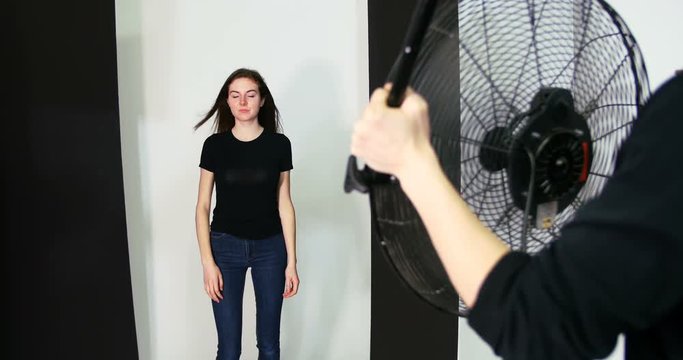 Photographer holding fan for female model during photo shoot