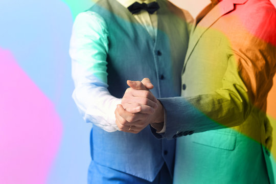 Happy gay couple dancing against color background