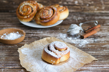 Fresh Delicious  cinnamon  rolls with powdered sugar on wooden table. Sweet food backround.