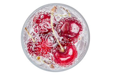 Ripe and sweet cherries in a glass of sparkling soda water placed on white background, healthy drinking concept.