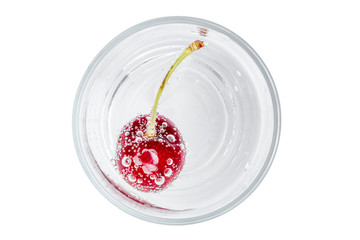 Top view of sweet shiny cherry in soda water with bubbles of carbon dioxide on white background.