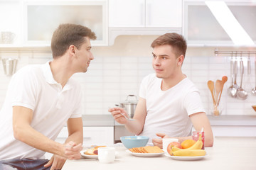 Obraz na płótnie Canvas Happy gay couple having breakfast in kitchen