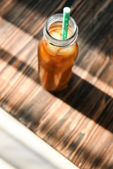 Glass bottle of cold brew coffee on wooden table