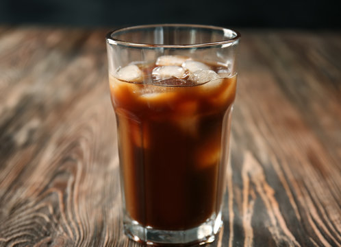 Glass with cold brew coffee and milk on wooden table