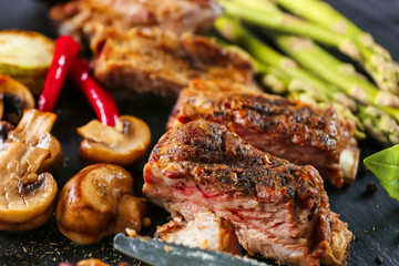 Delicious grilled spare ribs with vegetables on black slate plate