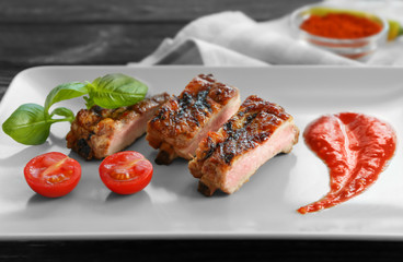 Delicious grilled spare ribs with cherry tomatoes and spicy sauce on white plate
