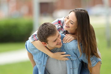 Happy couple of teens joking outdoors