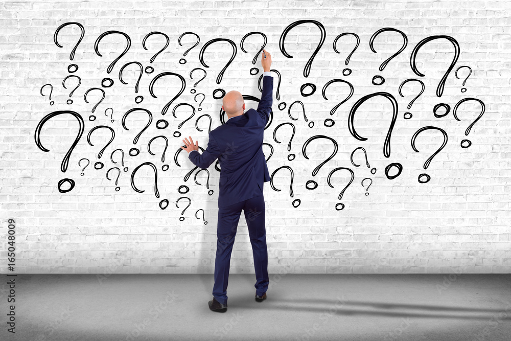 Poster view of a businessman in front of a wall trying to find find answers - daily life concept