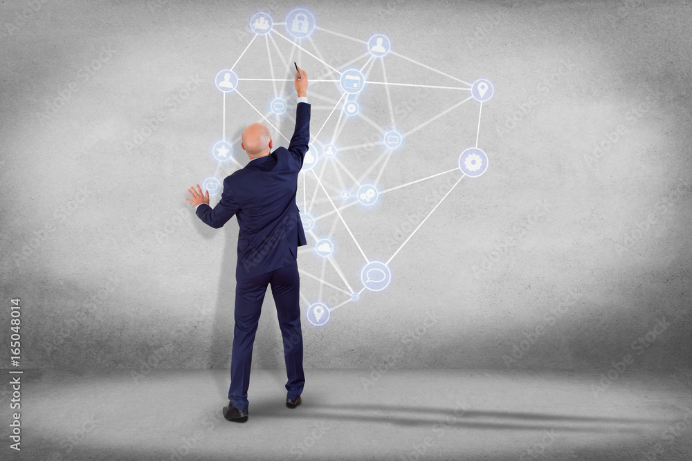 Poster businessman in front of a wall with a business network connection displayed on a futuristic interfac