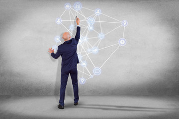 Businessman in front of a wall with a business network connection displayed on a futuristic interface with technology icon - Worldwide business concept