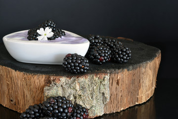 Blackberries with yogurt on black wooden background