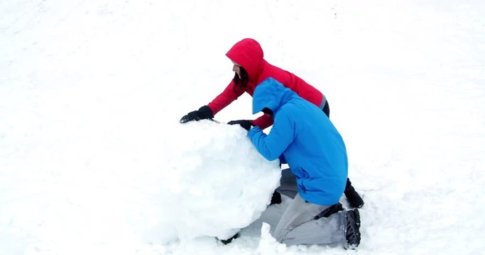 Couple pushing a huge snowball