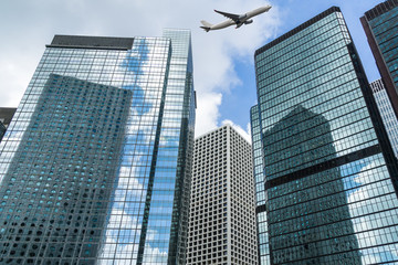 Skyscrapers from a low angle view with a plane flying over in city of China.