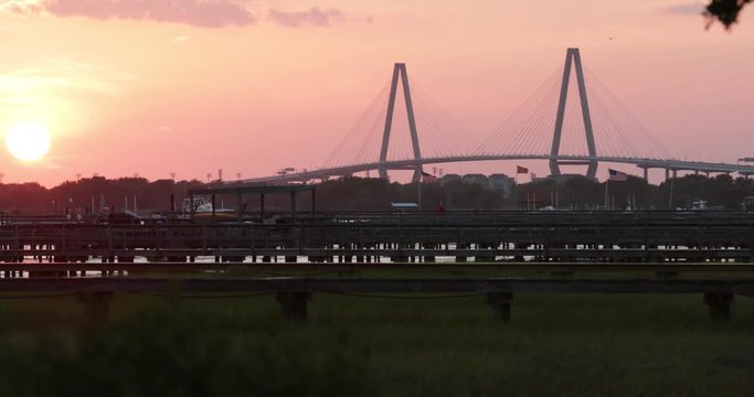 The Charleston Ravanel bridge at sunset with a marsh in foreground, flags waving.