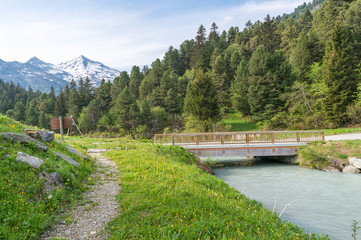 Fototapeta na wymiar Bridge crossing a glacial river in front of the French Alps.