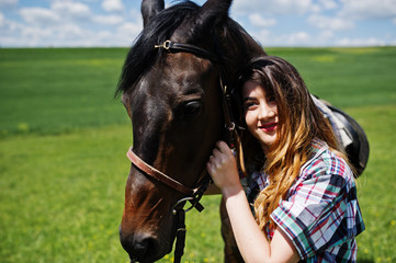 Obraz premium Young pretty girl stay with horse on a field at sunny day.