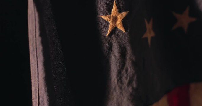 American flag with 13 stars of the revolution hangs with strong lighting.