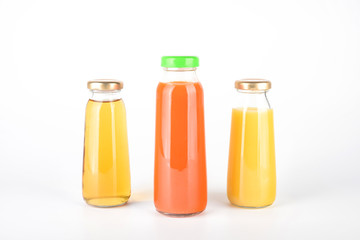 Apple, orange and carrot juice in bottles. Fruit and vegetable soft drink in a glass bottles isolated on white background 