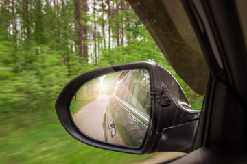 A view in the side view mirror. Mirror rear car. Reflection of the road